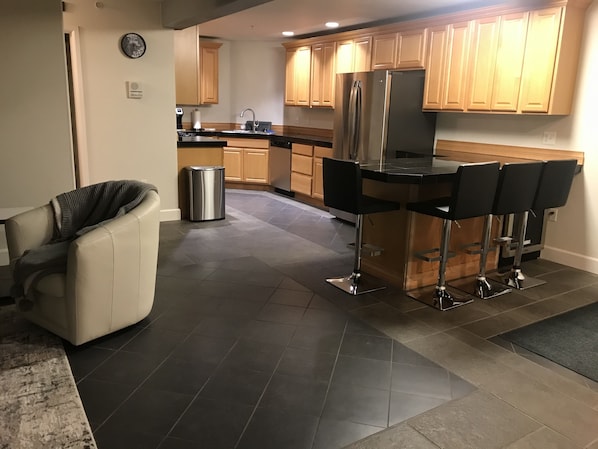 Een moderne keuken met een roestvrijstalen koelkast, houten keukenkastjes en een bar met krukken.