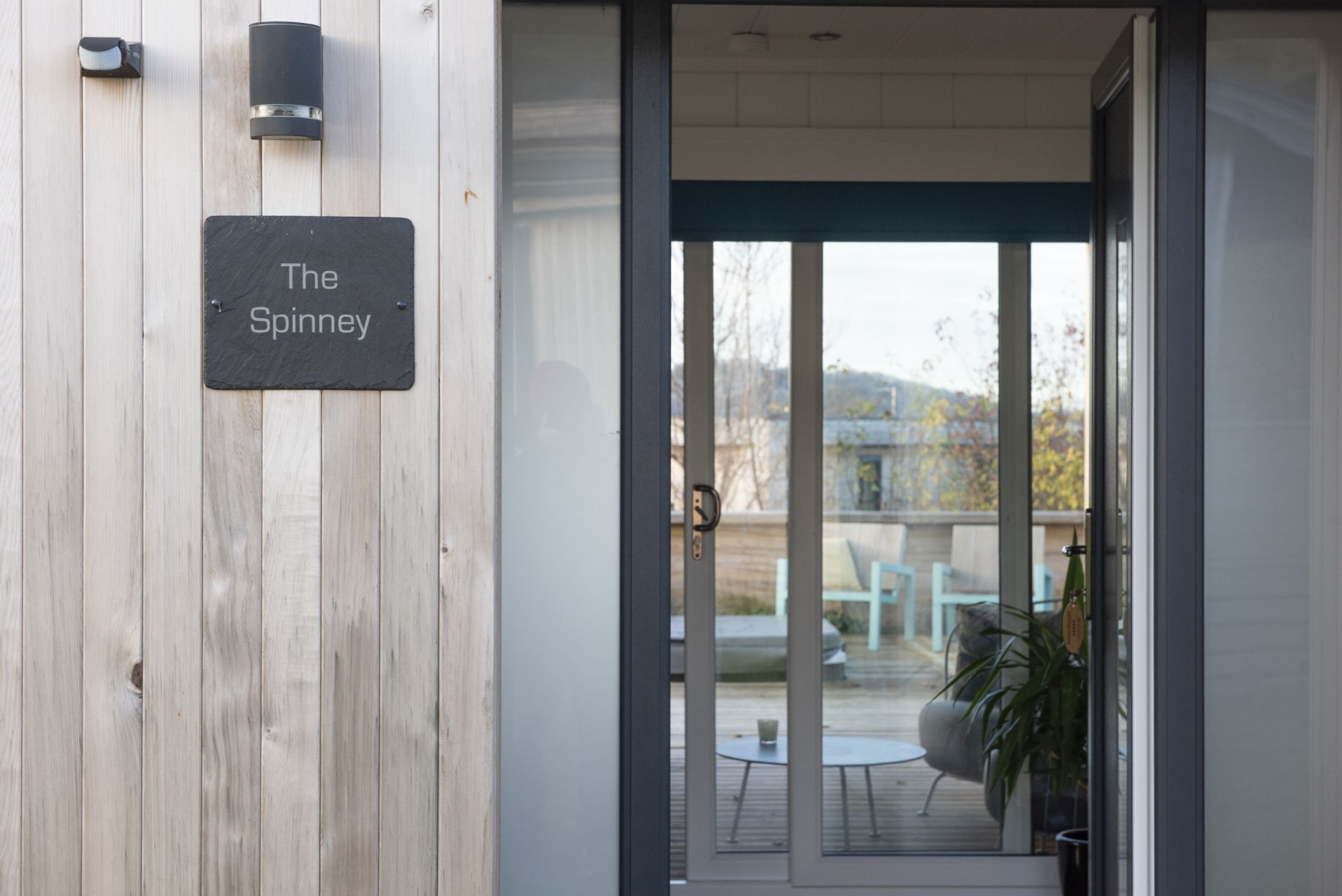 Un muro esterno in legno con un cartello che riporta la scritta 'The Spinney'.