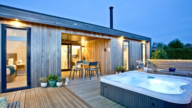 Een modern buitengebied met een jacuzzi, een houten terras en een eethoek.