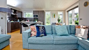 Een moderne keuken met donkere kastjes, een centraal eiland en een eethoek met een tafel en stoelen.