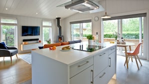 A modern kitchen with a large island, a built-in stove, and a dining area with a view of the garden.