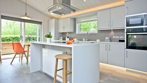 A modern kitchen with a central island, white cabinetry, and a large window providing natural light.