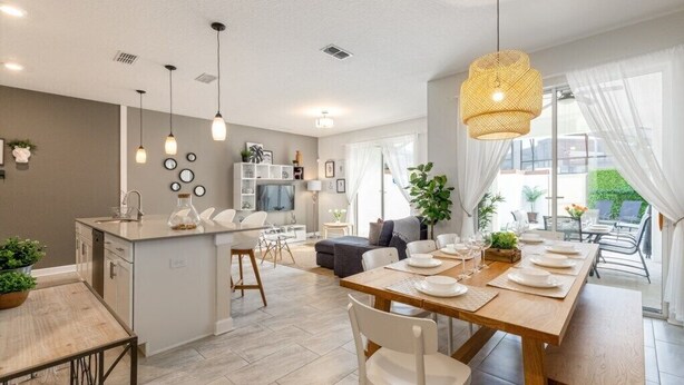 A modern kitchen and dining area with a central island, pendant lighting, and a view of the outdoors. - Storey Lake - LUXURY 4 bedrooms, 3 bath, private pool -  Star Wars & Mickey theme (Kissimmee)