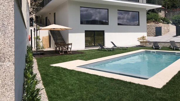 Una casa moderna de dos pisos con piscina, un patio cubierto y una escalera que lleva al piso superior.