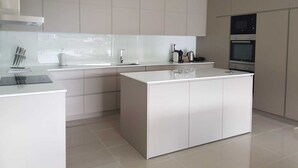 Una cocina moderna con una isla central, electrodomésticos de acero inoxidable y un amplio ventanal que proporciona luz natural.