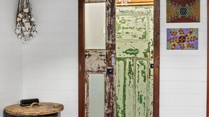 A rustic door with peeling paint, a hanging cotton branch decoration, and two framed artworks on the wall.