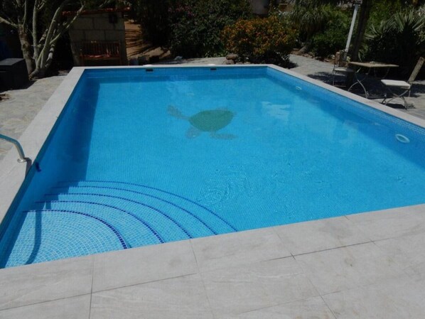 A rectangular swimming pool with a clear blue water surface, surrounded by a tiled deck.