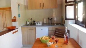A compact kitchen with wooden cabinets, a sink, and a dining area with a table set for two. - Calma, quiet studio with sea view terrace overlooking the pool (Las Zocas)