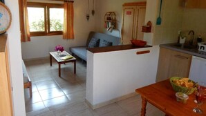 A cozy living area with a sofa, a small table with a vase, and a kitchen area with a sink and cabinets. - Calma, quiet studio with sea view terrace overlooking the pool (Las Zocas)