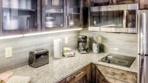 A modern kitchen with stainless steel appliances, a granite countertop, and wooden cabinets.