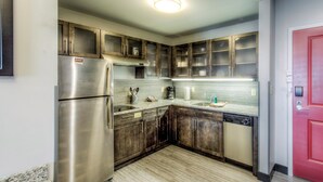 Una cocina con armarios de madera, un refrigerador de acero inoxidable, un lavavajillas y salpicadero de azulejos.