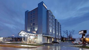 Un hotel de varios pisos con una entrada destacada y un área techada.