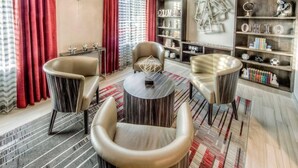 Una sala de estar moderna con sillones de cuero, una mesa de centro redonda y una estantería con adornos.