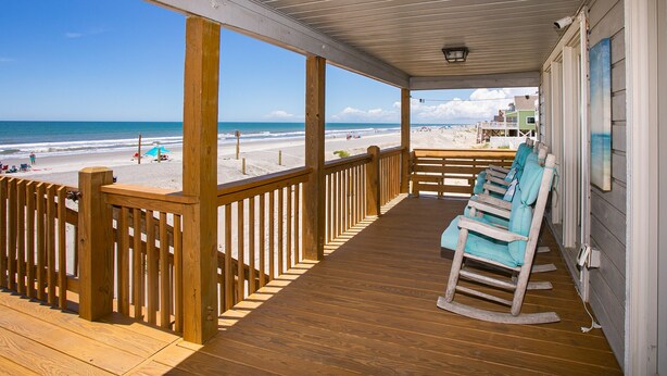 A wooden deck with a railing overlooking a beach. - Out Of Office: Dog-friendly, Oceanfront Home on West Beach with Corn Hole and Ho (Oak Island)