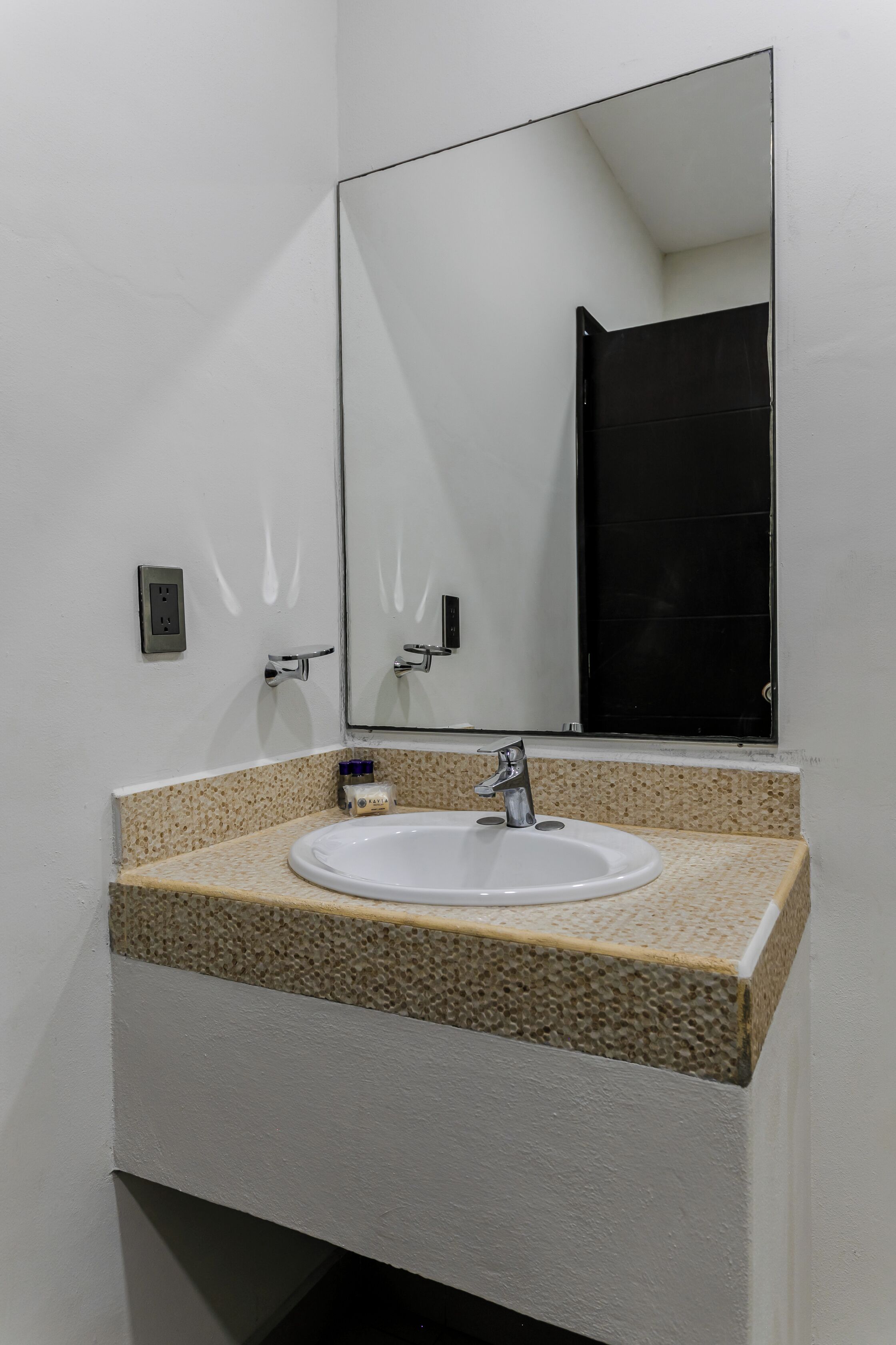 Un baño con lavamanos blanco, encimera de granito y un espejo grande.