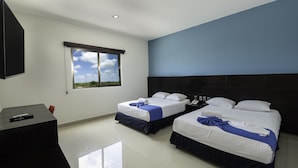 Habitación de hotel con dos camas, un escritorio y una ventana con vista al cielo.