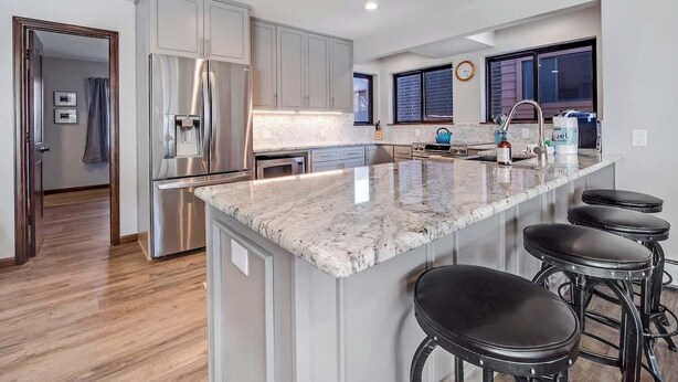 Una cocina moderna con una isla grande, electrodomésticos de acero inoxidable y una zona con taburetes de bar.