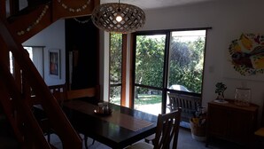 A dining area with a wooden table, chairs, and a hanging light fixture.