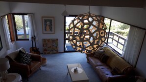A living room with a brown leather sofa, a white coffee table, and a hanging light fixture.