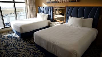 Une chambre d’hôtel avec deux lits, une grande fenêtre donnant sur un parking et un miroir au-dessus des lits.