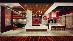 A modern hotel lobby with a reception desk, seating area, and a large wall with a circular design.