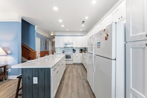 A modern kitchen with white cabinetry, a central island, and a wooden floor.