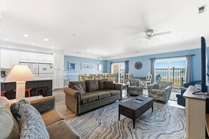 A spacious living area with a sofa, chairs, a coffee table, and a view of the ocean.