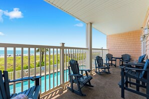 Ein überdachter Außenbereich mit Pool, Stühlen und Blick auf den Strand.