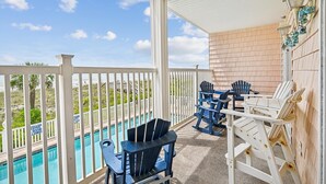 A balcony with a pool, white railings, and outdoor seating.