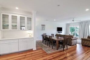 Enjoy a spacious living area with a dining table, sofa, and TV, plus a well-equipped kitchen with glass-front cabinetry.