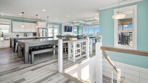 Una cocina amplia con una isla grande, muebles blancos y vistas al exterior.