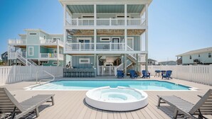 Un edificio de varios pisos con piscina, zona de estar al aire libre y jacuzzi.
