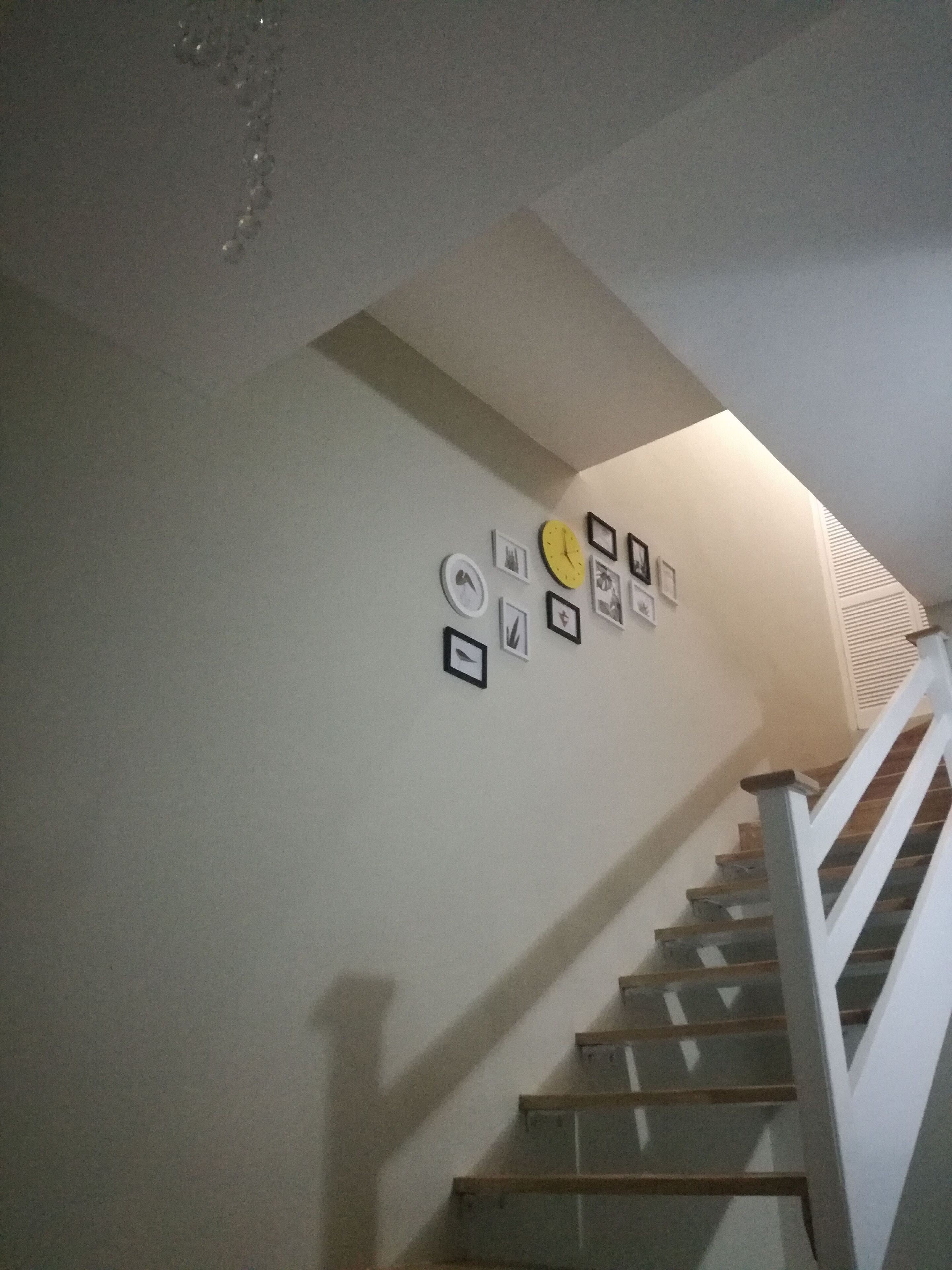 A staircase with a white railing and a wall decorated with framed pictures.