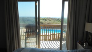 A hotel room with a large bed, a view of a pool, and a deck area.