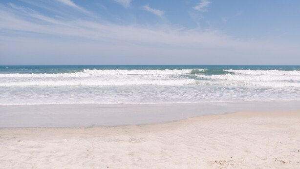 A beach with waves and a clear sky.