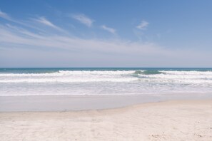 A beach with waves and a clear sky.