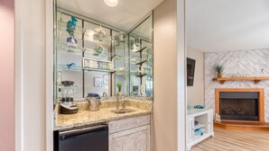 A kitchen with a built-in dishwasher, a granite countertop, and a glass display cabinet with decorative items.