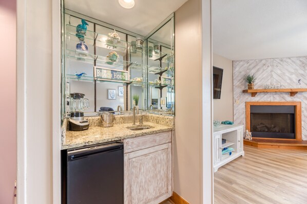 A kitchen with a built-in dishwasher, a granite countertop, and a glass display cabinet with decorative items.
