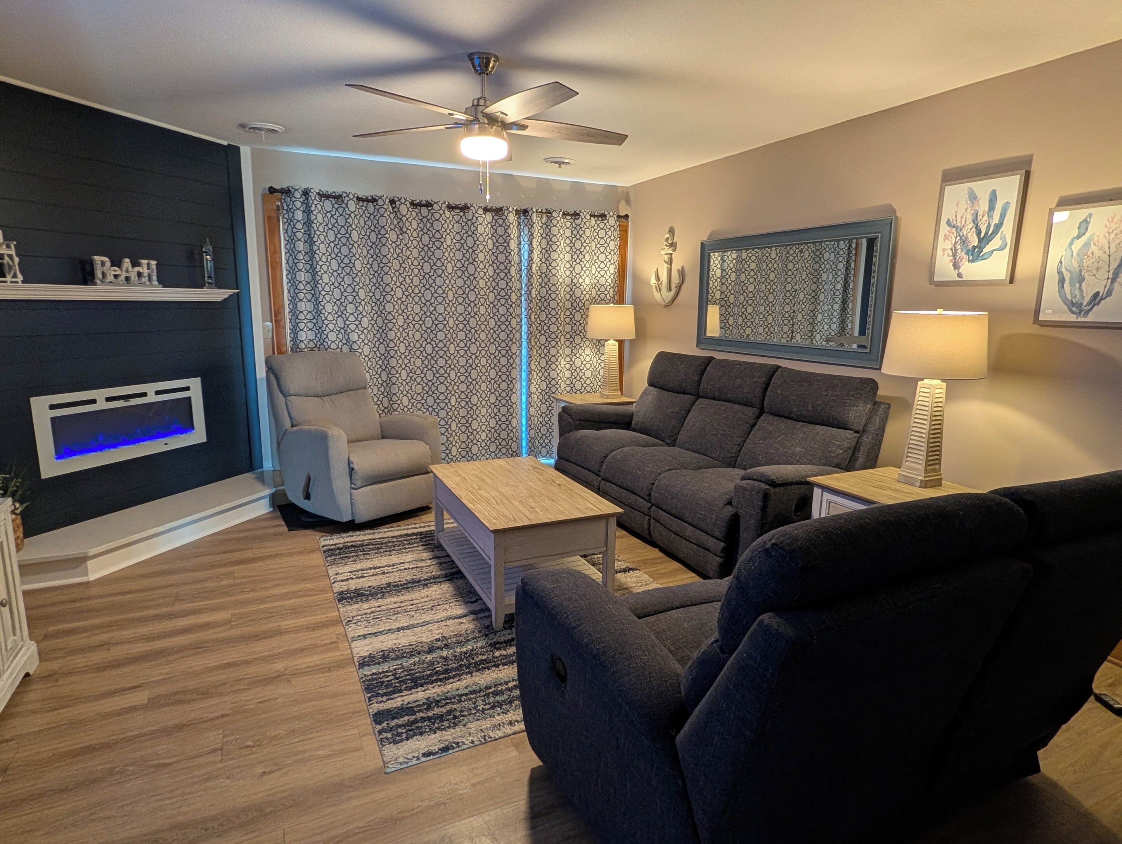 A living room with a fireplace, ceiling fan, and modern decor.