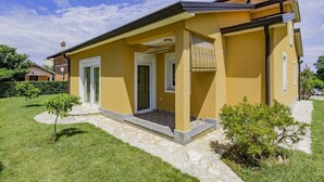 A yellow house with a stone pathway, a small garden, and a clear blue sky. - Apartment in a quiet location (Umag)
