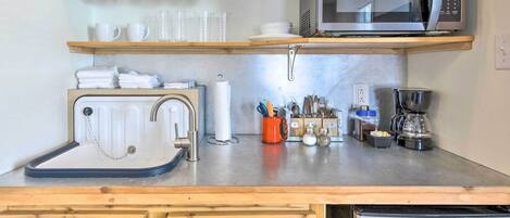 Une cuisine compacte équipée d’un four à micro-ondes, d’une bouilloire et d’une machine à café.