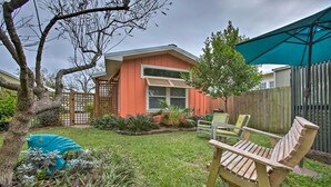 Un patio trasero con un banco de madera, un paraguas turquesa y una valla de madera.