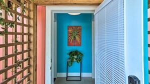 Un pasillo con celosía de madera, una planta en maceta y un letrero que dice 'WELCOME' en una pared azul.