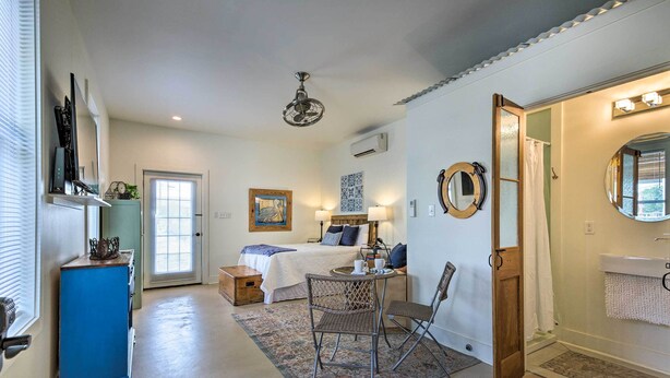 Una habitación acogedora con una cama, una pequeña mesa con sillas, un armario azul y una puerta que da a un baño.