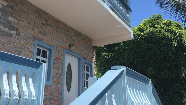 Un edificio con facciata in pietra, un balcone con ringhiere bianche e un cielo azzurro intenso.