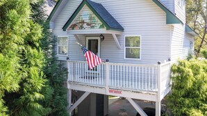 A house with a balcony, a porch, and a flag. - Cabin on the River - In Town on the Chattahoochee River (Helen)