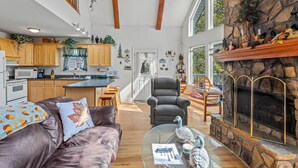 A spacious living room with a leather sofa, a glass coffee table, and a fireplace. - Cabin on the River - In Town on the Chattahoochee River (Helen)