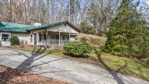 A single-story house with a green roof, a porch, and a small front yard.