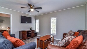 A living room with a gray sofa, a brown leather couch, a wooden coffee table, and a ceiling fan.