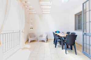 A bright, well-lit room with a dining table set for four, surrounded by chairs. There is a staircase on one side and a window on the other. - Cristallo apartment - child protection gate - beach under the house (Carovigno)